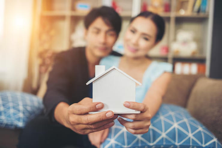 Young couple holding a miniature house in living room